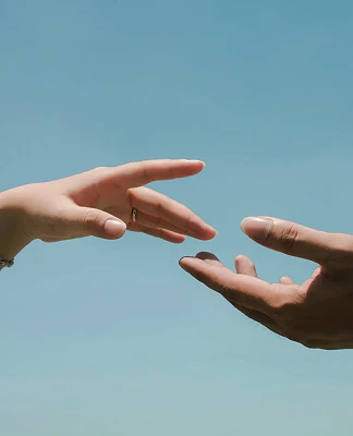 青空を背景に、お互いに向かって伸ばされた2人の手